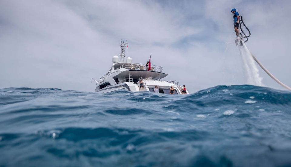 A person flies a water jetpack next to the Amore Mio yacht