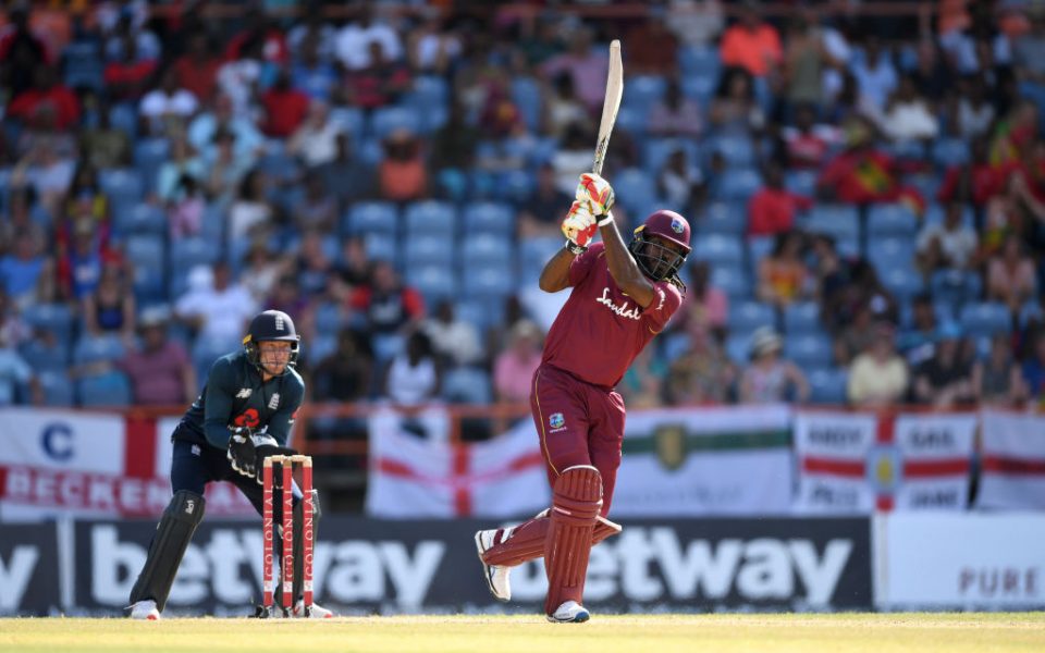 GRENADA, GRENADA - FEBRUARY 27: Chris Gayle of the West Indies hits out for six runs watched by England wicketkeeper Jos Buttler during the 4th One Day International match between the West Indies and England at Grenada National Stadium on February 27, 2019 in Grenada, Grenada. (Photo by Gareth Copley/Getty Images)